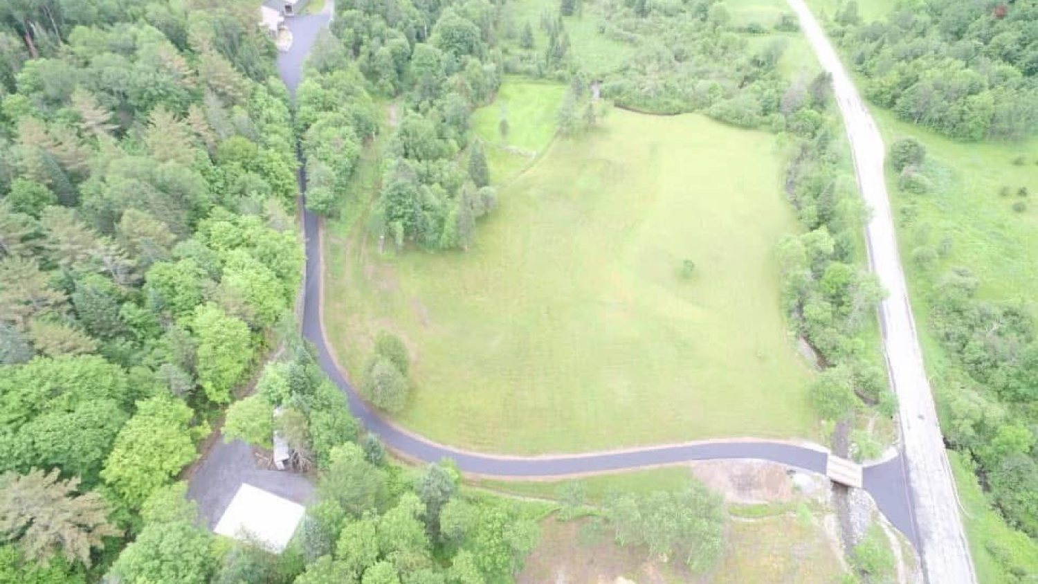 Aerial of a long winding driveway across a Vermont hayfield