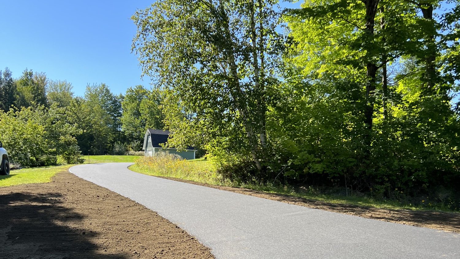 Country driveway curving through trees toward a barn