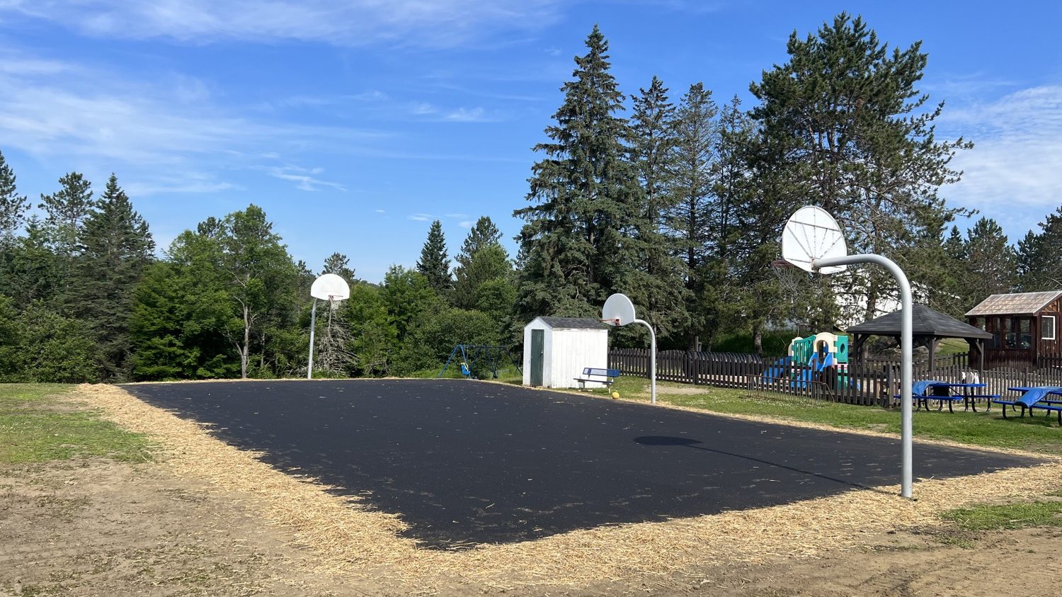 Asphalt basketball court with wood-chip border at a Vermont playground
