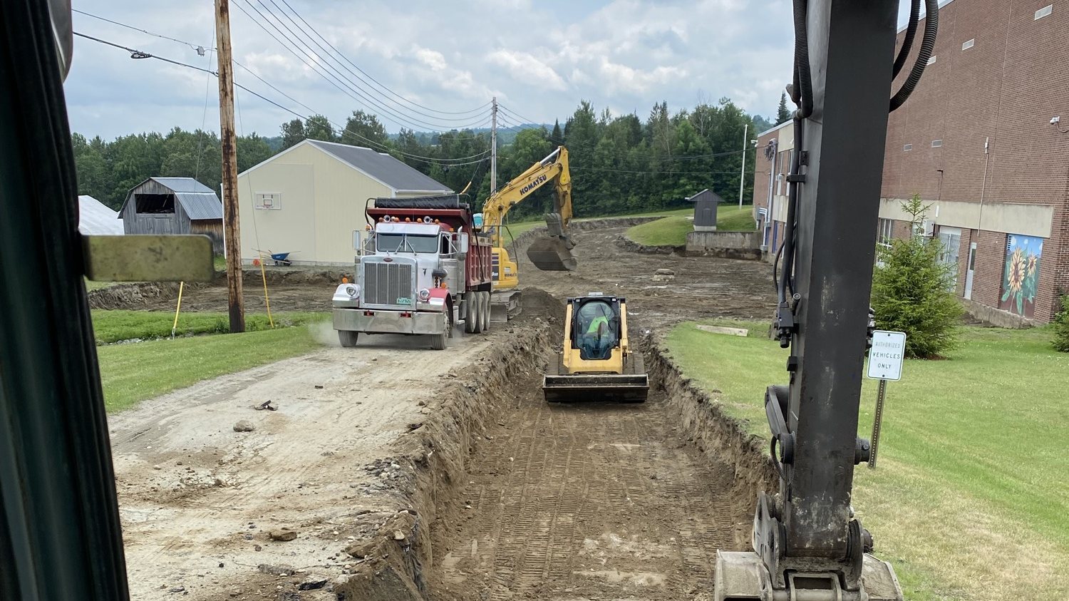 Excavation crew trenching a site with dump truck, excavator, and skid steer