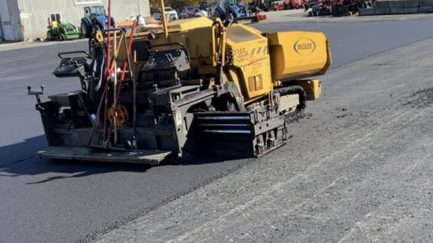 Weiler paver laying asphalt on a commercial lot in the fall